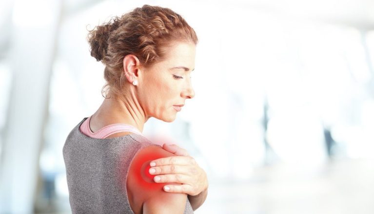 Portrait of sporty woman putting her hand on red spots on while has sport injury in her shoulder.