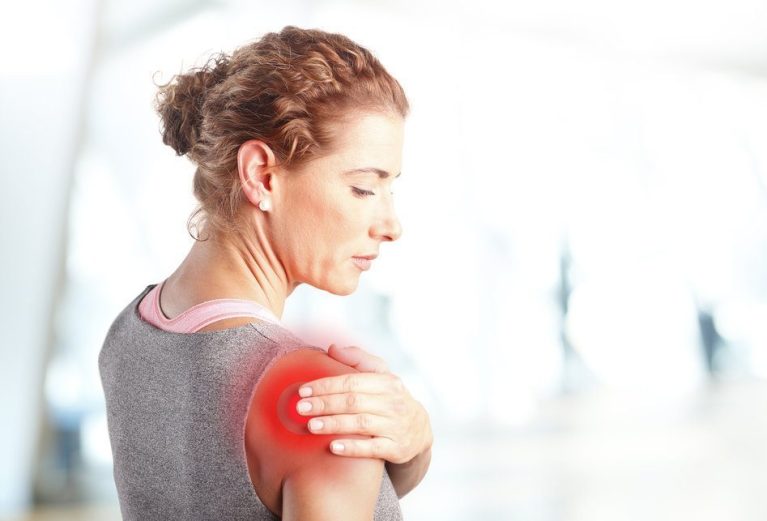 Portrait of sporty woman putting her hand on red spots on while has sport injury in her shoulder.